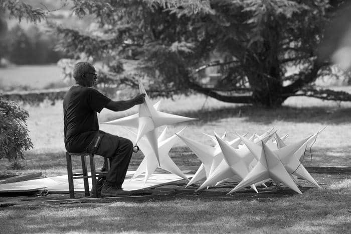 Personne assise en extérieur parmi de grandes structures en forme d’étoiles.